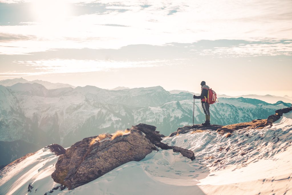 A backpacker standing atop snowy mountains, exploring the serene Himalayan landscape.